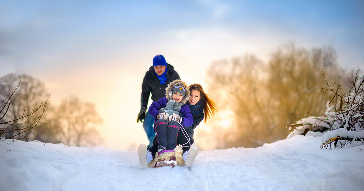 famille, père, mère enfant, sur une luge, glissade sur la neige devant un couché de soleil